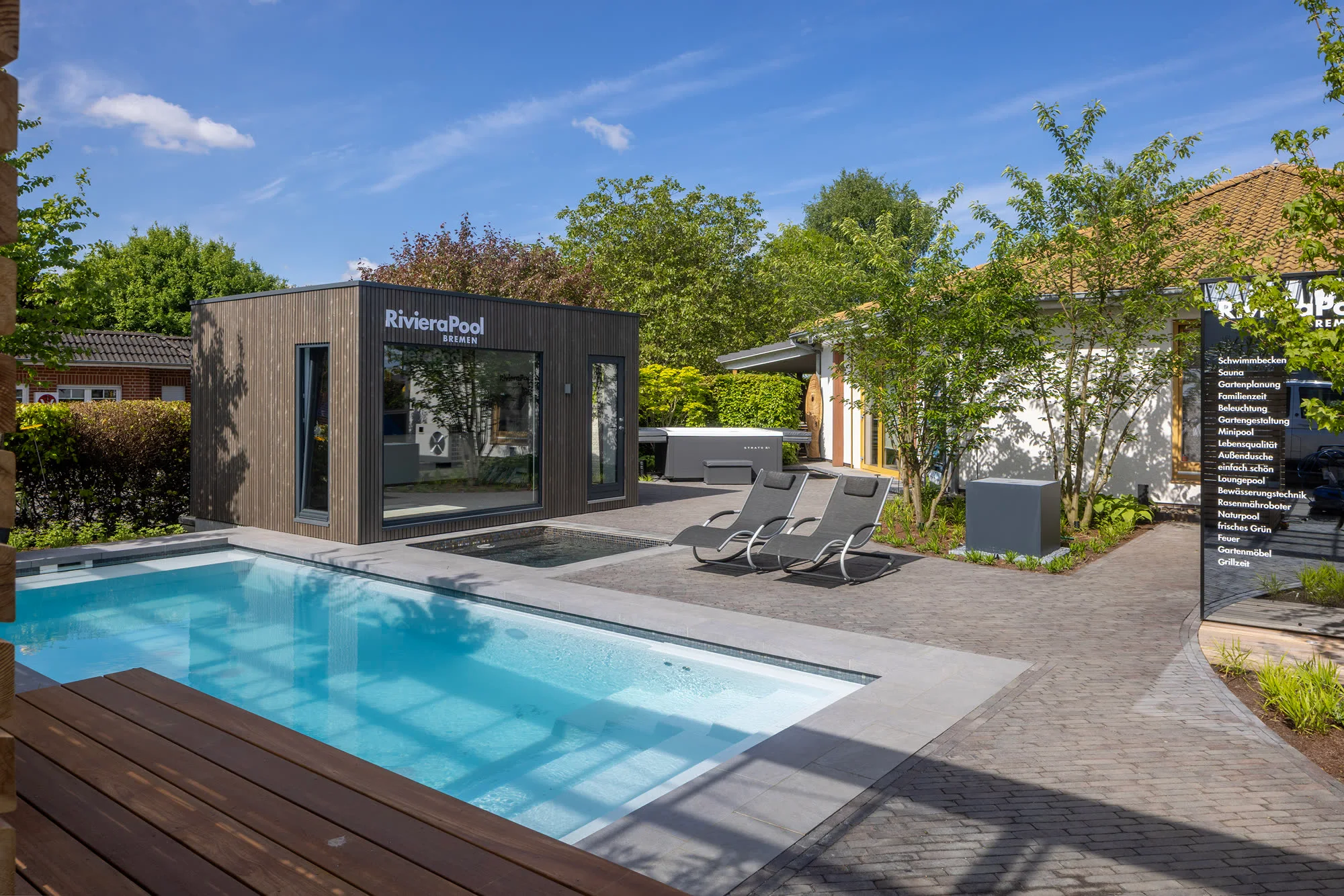 RivieraPool-Außenausstellung bei Sonnenschein: Außenbecken mit Liegen vor dem Showroom-Gebäude
