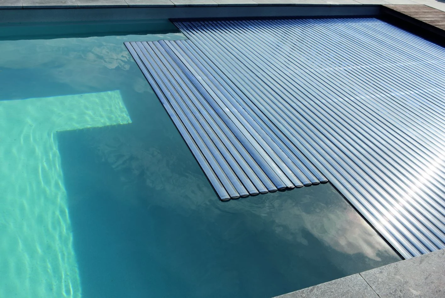 Echtes Foto eines Unterflurrollladens, dessen Lamellen über die Wasseroberfläche eines Pools fahren