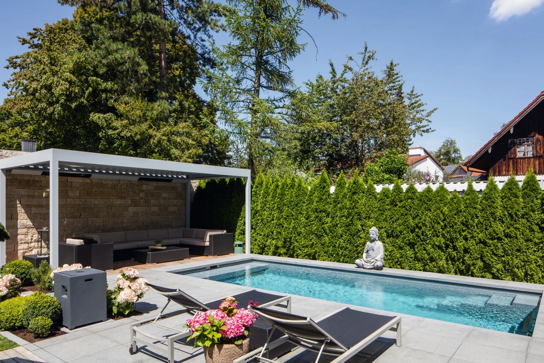 Fertig eingebautes RivieraPool-Schwimmbecken im Garten mit Loungebereich und Pergola